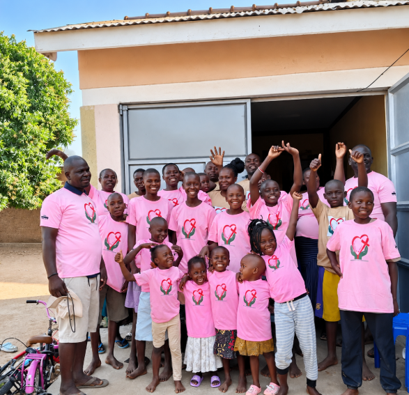 Children and staff from Mark of Hope International gathered outside in matching pink shirts in Uganda
