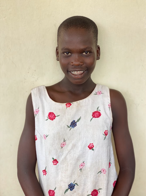 Esther smiling in a floral dress against a light wall