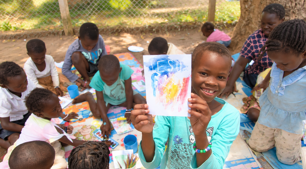 Children at Mark of Hope showing a colorful drawing of Jesus during an outdoor activity
